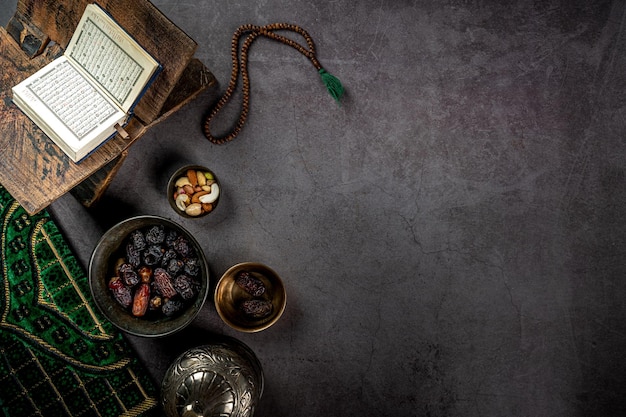 Corano aperto vicino al concetto di date del ramadan kareem su sfondo scuro con texture