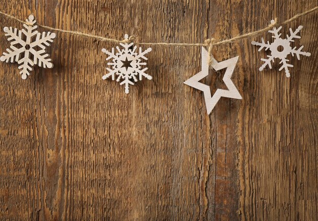 Corda con fiocchi di neve e stella su fondo in legno