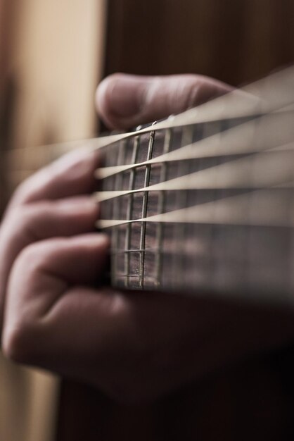 Corde dal suono dolce Inquadratura ritagliata di un uomo irriconoscibile che suona una chitarra acustica a casa