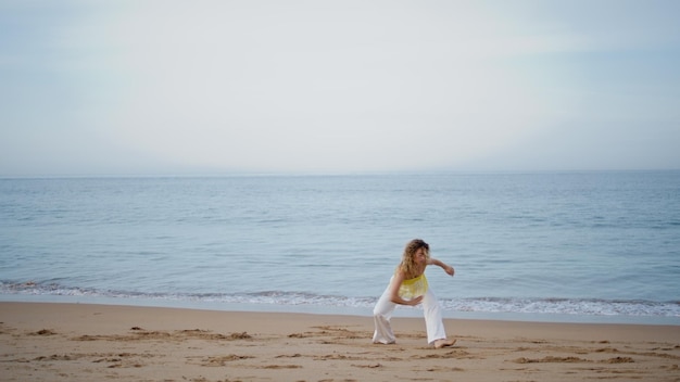 Coreografa ispirata donna che balla sulla costa del mare vuoto ragazza ballerina che muove il corpo