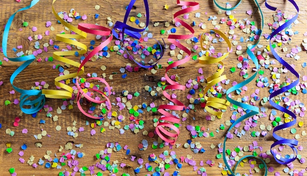 Coriandoli colorati di carnevale e serpentine su sfondo di legno in alto niew