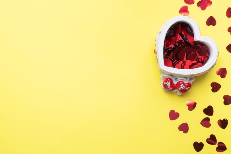 Foto coriandoli cuori rossi su supporto in ceramica a forma di cuore su sfondo giallo. biglietto di auguri per il giorno di san valentino. lay piatto.