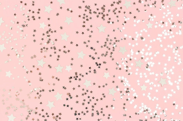 Coriandoli di stelle d'argento luminose su uno sfondo rosa pastello