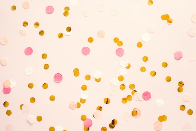 Coriandoli rotondi rosa e oro su una parete pastello rosa. Modello per pubblicità, blog, sconti e testo