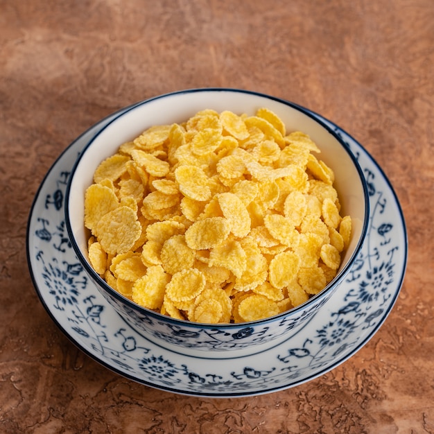 Corn flakes in un piatto su uno sfondo marrone.