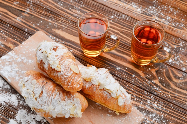 Cornetti con mandorle e tè su un tavolo di legno.