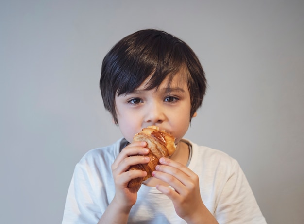 Cornetto bambino ragazzo per la sua colazione prima di andare a scuola la mattina