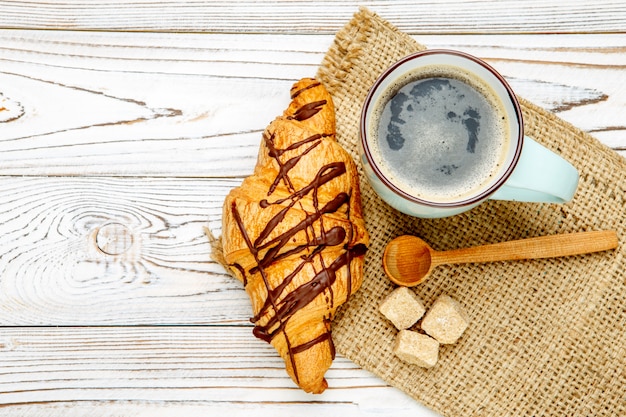 Cornetto e caffè freschi su fondo di legno