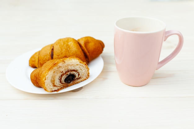 Cornetto fresco con cioccolato sulla tavola di legno bianca