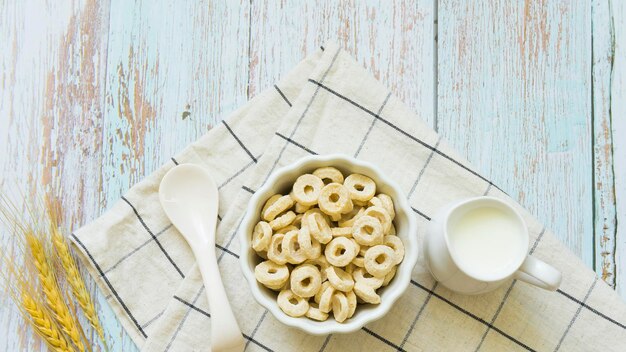 Cornflakes e brocca di latte su fondo in legno