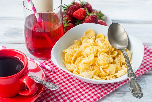 Cornflakes, fragole, latte e una tazza di caffè per colazione