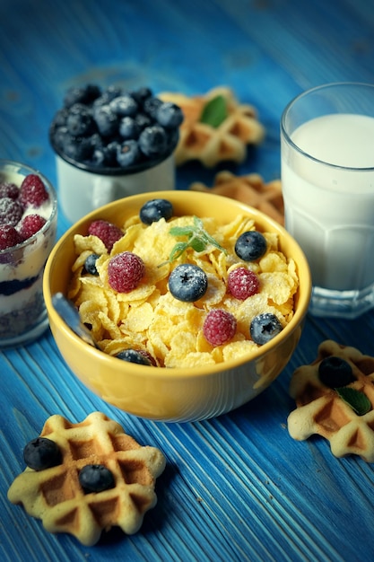 Cornflakes gustosi con lamponi e mirtilli su sfondo blu Wafer e latte