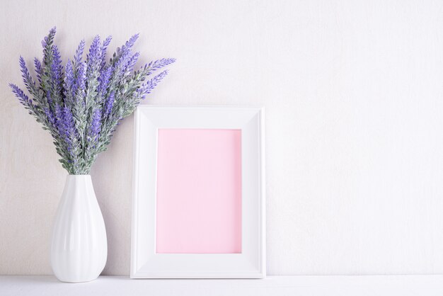 Cornice bianca con fiore viola adorabile in vaso sulla tavola di legno bianca