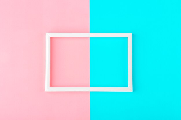Cornice bianca vuota su uno sfondo a due tonalità (blu, rosa) con spazio di copia per testo o lettere. Composizione minimale di linee geometriche. Vista dall'alto, piatto, mock up.