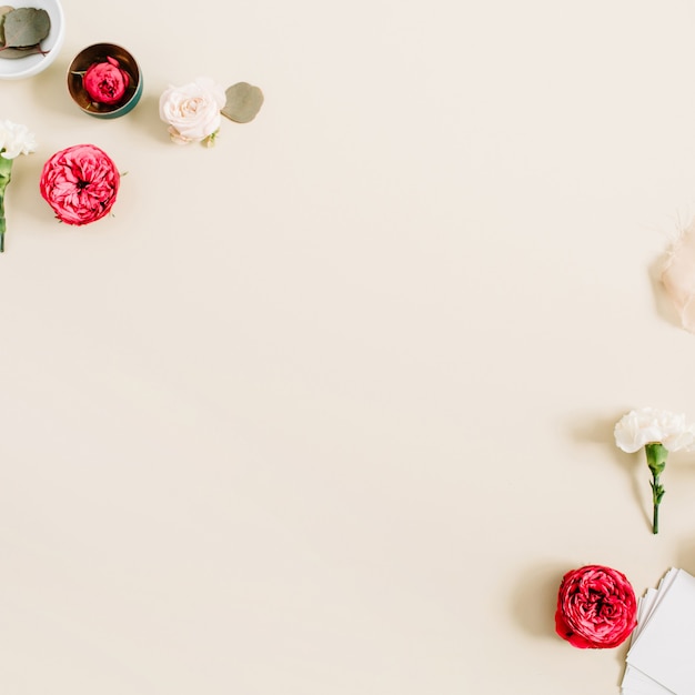 Cornice bordo fiori fatta di rose beige e rosse e garofano bianco su beige pastello chiaro