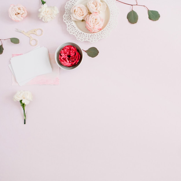 Cornice bordo fiori fatta di rose beige e rosse e garofano bianco su rosa pastello pallido