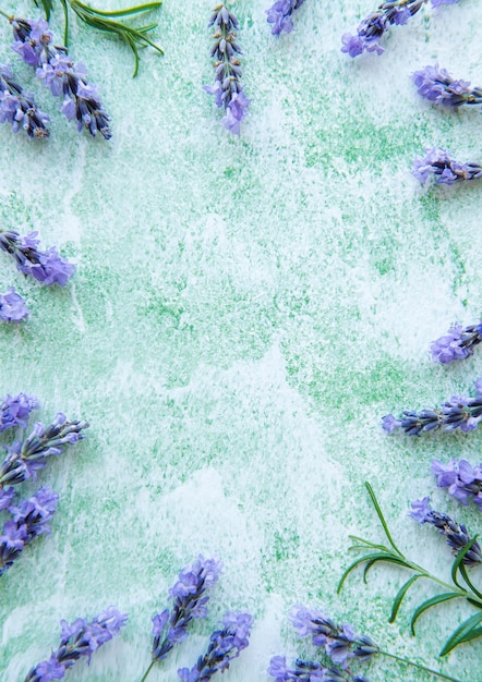 Cornice creativa di fiori e foglie di lavanda su uno sfondo di legno verde