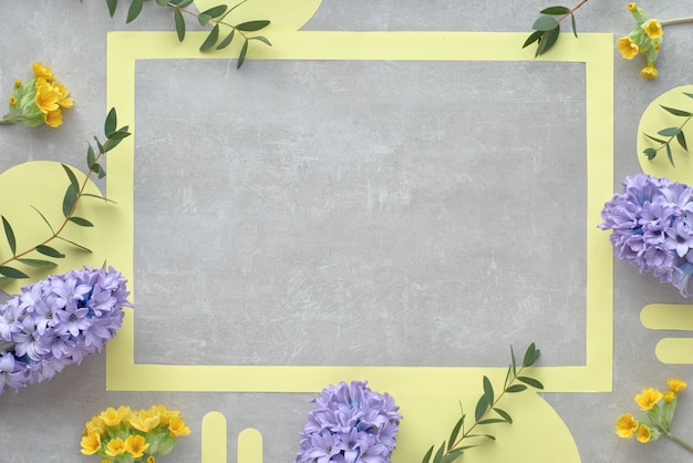 Cornice di carta gialla con spazio testo decorato con fiori di giacinto blu e foglie di eucalipto