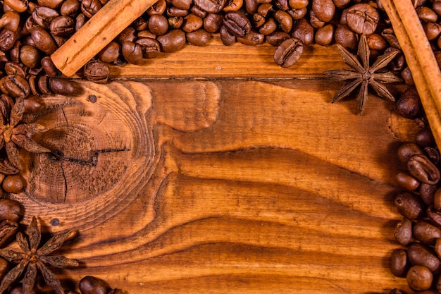 Cornice di chicchi di caffè, anice stellato e bastoncini di cannella su tavola in legno rustico