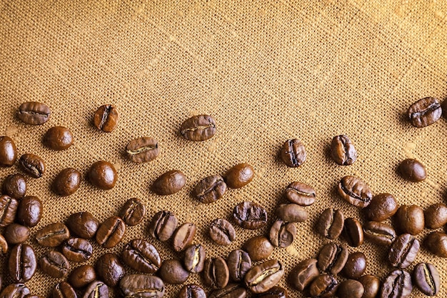 Cornice di chicchi di caffè su sfondo di tela di sacco a colori