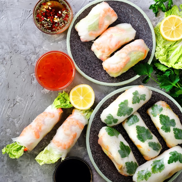 Cornice di cibo cinese asiatico vietnamita fresco su sfondo grigio cemento Involtini primavera carta di riso insalata di lattuga vermicelli tagliatelle gamberetti salsa di pesce peperoncino dolce soia limone Vista dall'alto