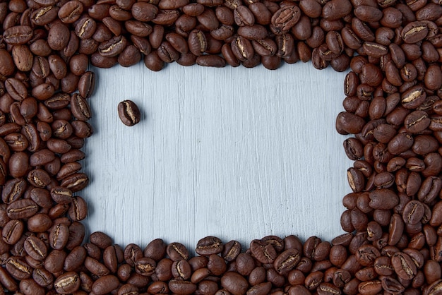 Cornice di design fatta di chicchi di caffè su un tavolo di legno blu. Mockup di presentazione