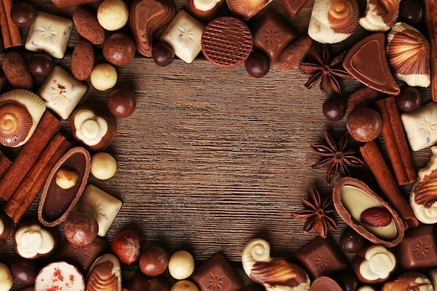 Cornice di diversi tipi di cioccolatini sul primo piano della tavola di legno