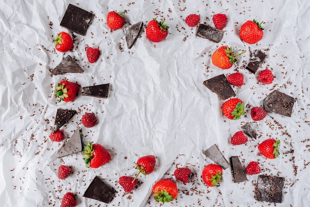 Cornice di fragole e lamponi e cioccolato amaro con uno sfondo di carta alla menta