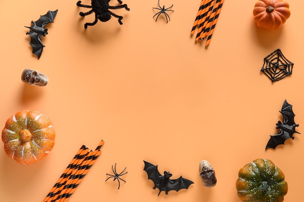 Cornice di Halloween di divertenti decorazioni per feste, zucche, cannuccia, pipistrelli, teschi, ragno spettrale su sfondo arancione.