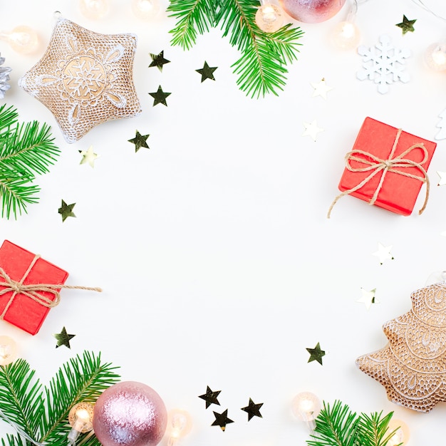 Cornice di Natale con rami di abete, luci di Natale, decorazioni rosa e beige su bianco