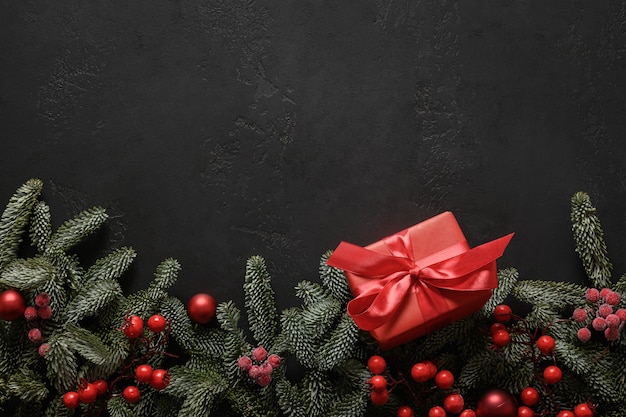 Cornice di Natale con regalo rosso e decorazioni su biglietto di auguri di Natale nero