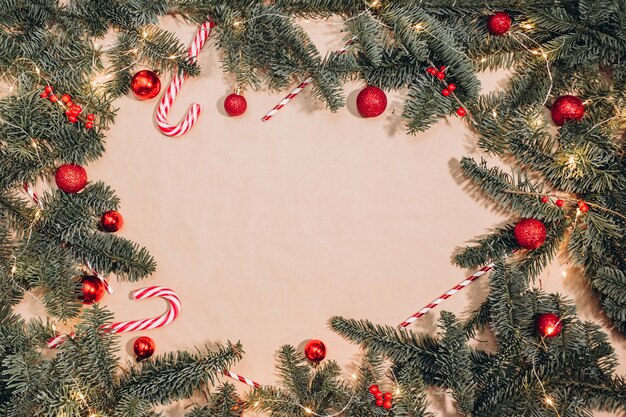 Cornice di Natale di rami di abete, palline rosse, bastoncini di liquirizia, sfondo di ghirlande