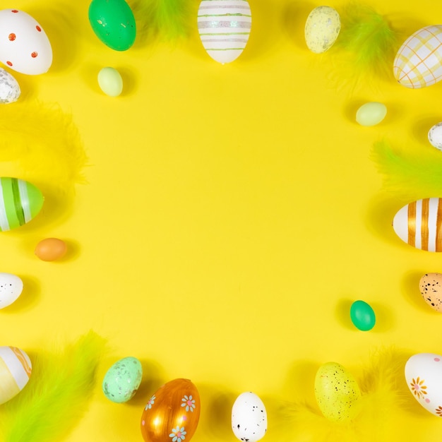 Cornice di Pasqua con uova e piume su sfondo giallo Vista dall'alto Scheda con copia spazio per il testo