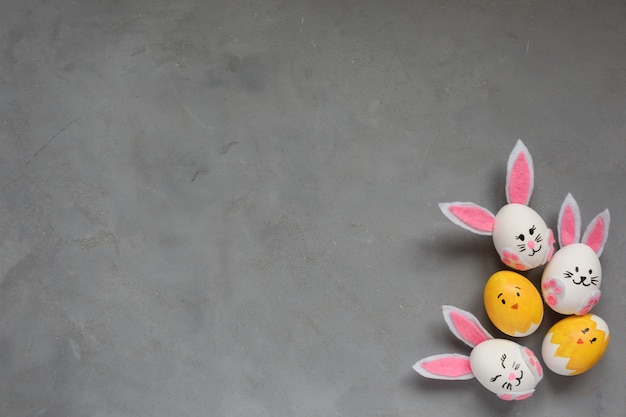 Cornice di Pasqua, uova colorate dipinte, coniglietti e pulcini su sfondo grigio. Copia spazio.