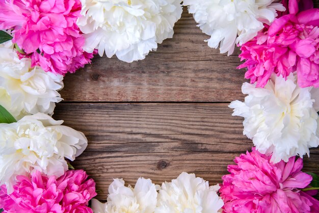 Cornice di peonie bianche e rosa su fondo in legno