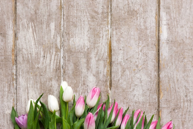 Cornice di tulipani rosa su fondo di legno. Mazzo di fiori nel posto di lavoro del fiorista con copyspace. Matrimonio, regalo, compleanno, 8 marzo, concetto di biglietto di auguri per la festa della mamma