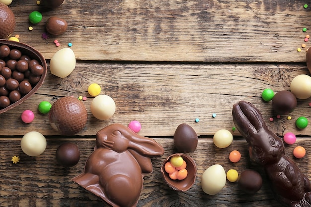 Cornice di uova di Pasqua al cioccolato conigli e dolci su fondo di legno