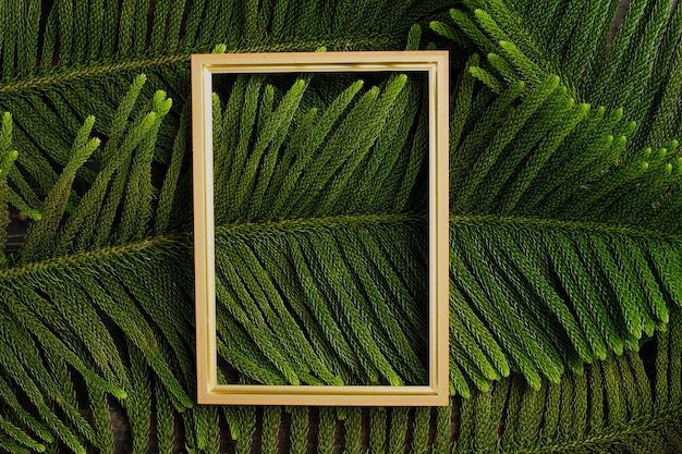 Cornice dorata di Natale con foglia di pino e decorazioni di palline su tavola di legno