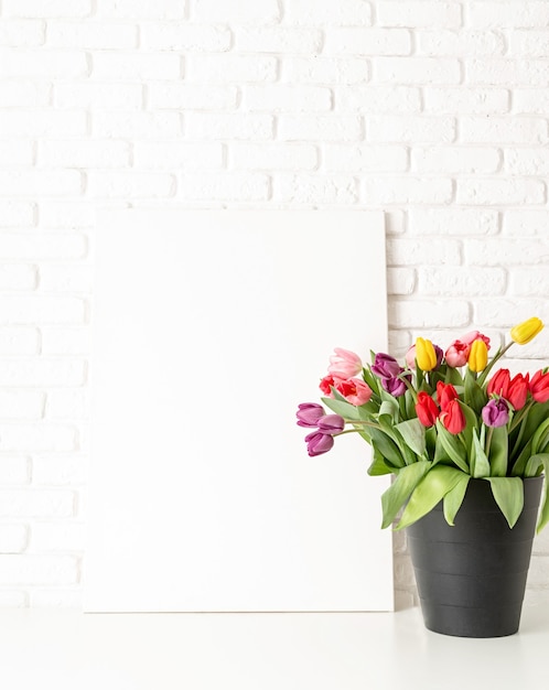 Cornice e secchio di tulipani su sfondo bianco muro di mattoni