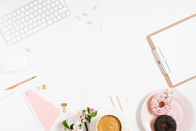 Cornice elegante e alla moda per una ciambella con tastiera per tablet notebook blogger freelance femminile su un piatto fiori di mela su uno sfondo bianco con un posto da copiare