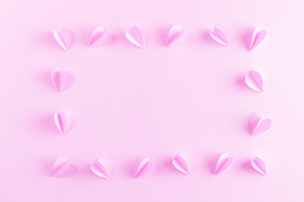 Cornice fatta da cuori rosa su sfondo di carta rosa pastello. San Valentino