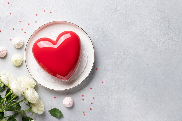 Cornice fatta di fiori di rosa, torta di mousse a forma di cuore e dolci