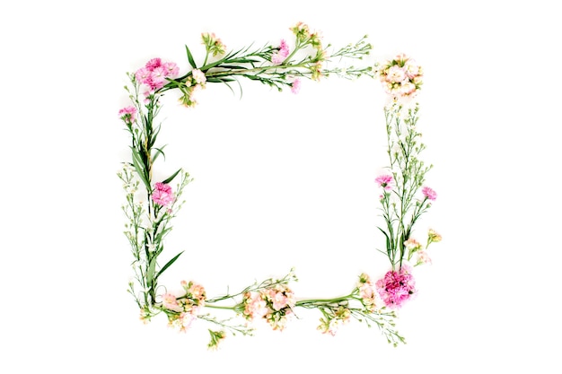 Cornice ghirlanda fatta di fiori di campo rosa e beige, foglie verdi, rami su bianco