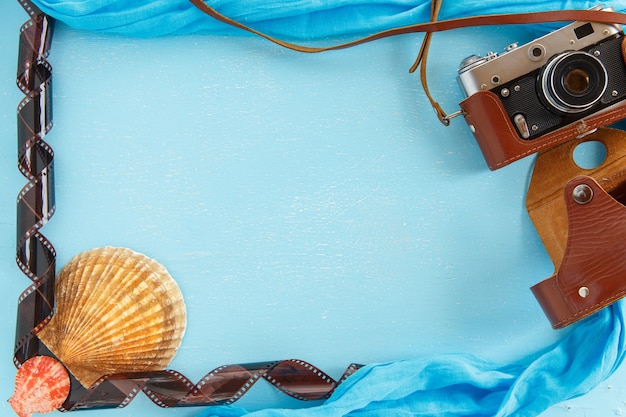 Cornice in carta bianca con stelle marine, conchiglie e oggetti sulla tavola di legno.