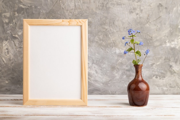 cornice in legno con fiori blu del nontiscordardime in vaso di ceramica su sfondo grigio cemento. vista laterale