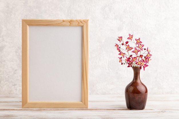 cornice in legno con fiori di barenwort viola in vaso di ceramica su sfondo grigio cemento. copia spazio