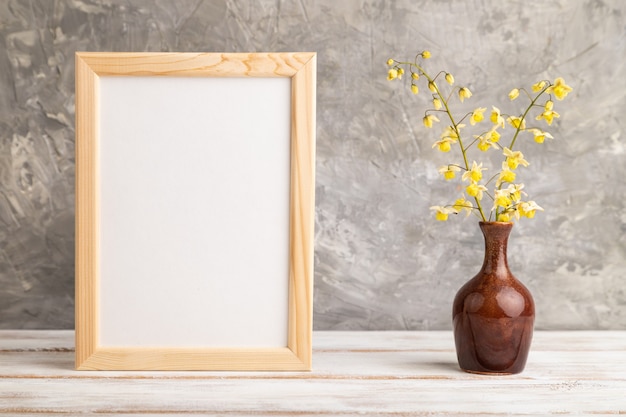 cornice in legno con fiori gialli di barenwort in vaso di ceramica su sfondo grigio cemento. copia spazio