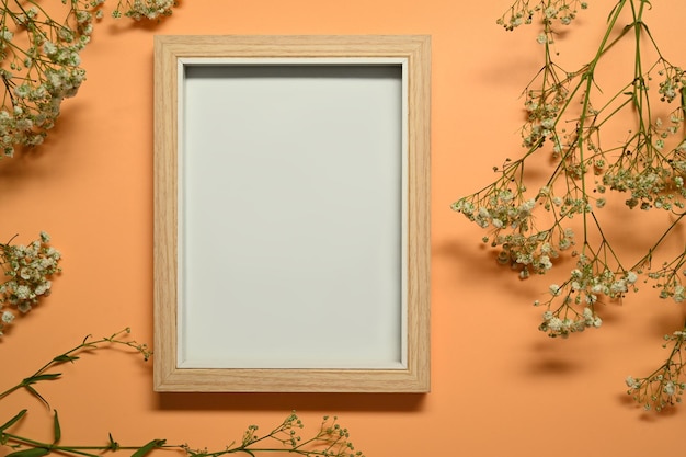 Cornice in legno vuota circondata da gypsophila bianca o fiori di respiro del bambino su sfondo nero