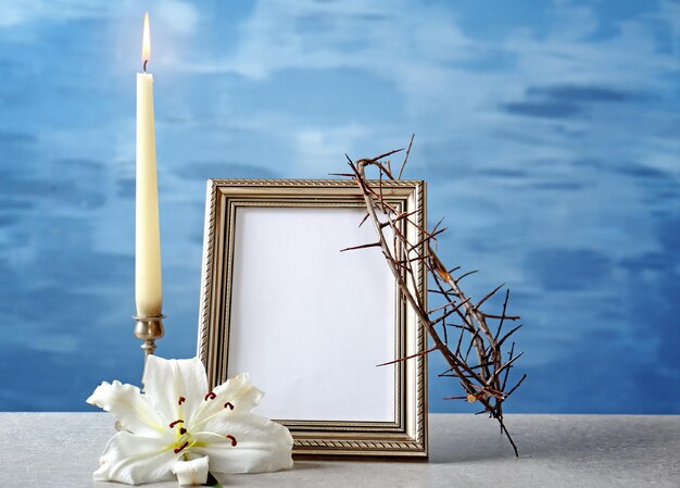 Cornice per foto corona di spine giglio e candela su sfondo chiaro