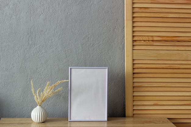 Cornice per foto in bianco per mockup di decorazioni per la casa vicino al muro di cemento verniciato grigio Posto per il testo